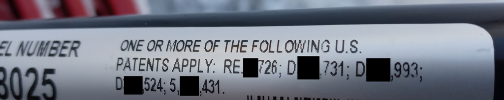 Redacted photo of conditional patent marking notice on a product that reads "ONE OR MORE OF THE FOLLOWING U.S. PATENTS APPLY: RE[]726; D[],731; D[].993; D[],524; 5,[],43."